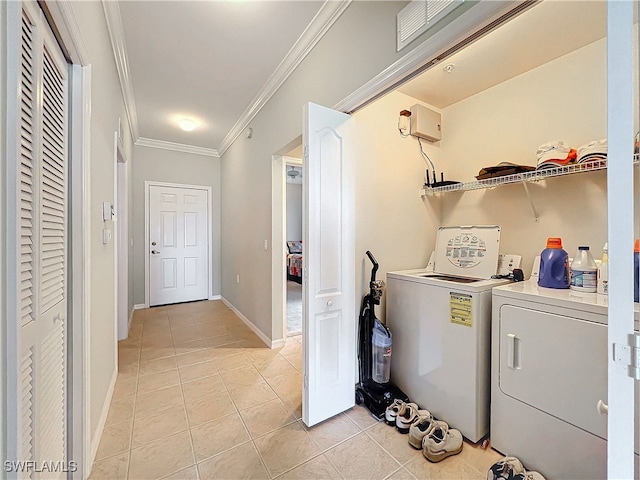 clothes washing area with washing machine and dryer, light tile patterned floors, and ornamental molding