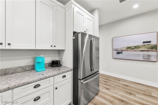 kitchen with stainless steel fridge, white cabinets, and light wood-type flooring