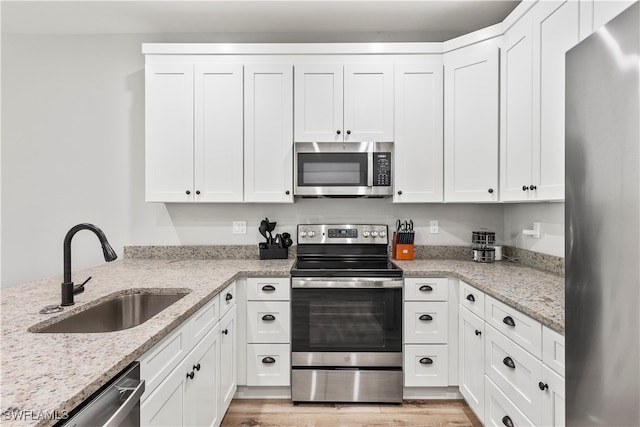 kitchen featuring white cabinetry, stainless steel appliances, sink, and light wood-type flooring