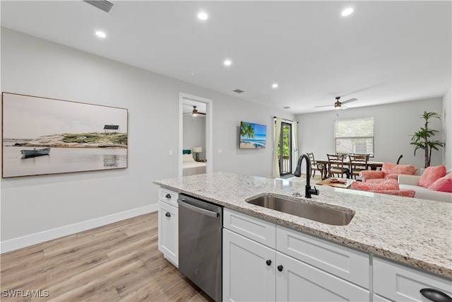 kitchen with sink, light stone countertops, light wood-type flooring, stainless steel dishwasher, and white cabinets