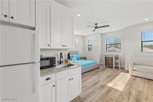 kitchen with sink, white cabinetry, white fridge, and light wood-type flooring