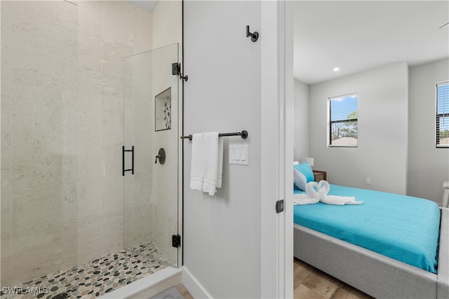 bathroom with a shower with shower door and hardwood / wood-style floors