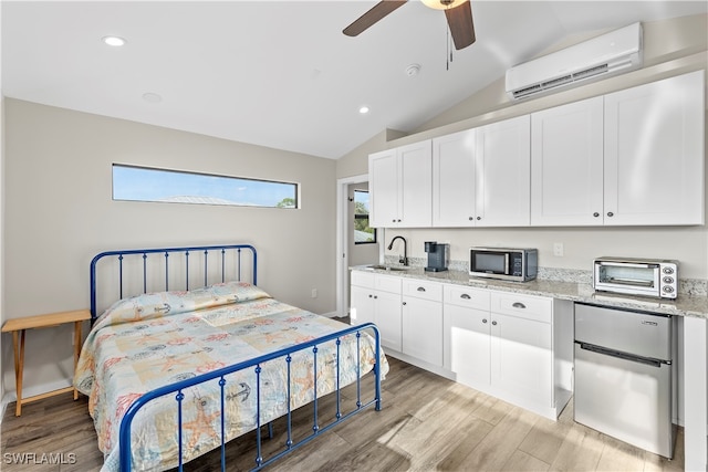 bedroom with a wall mounted air conditioner, ceiling fan, lofted ceiling, stainless steel refrigerator, and light hardwood / wood-style flooring