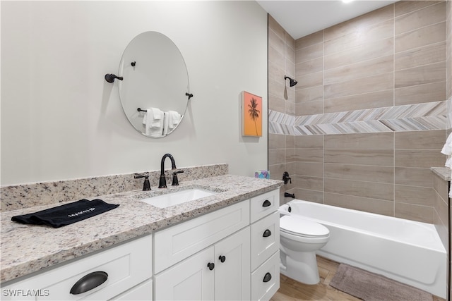 full bathroom featuring vanity, tiled shower / bath, and toilet