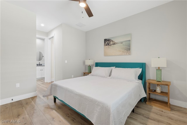 bedroom with light hardwood / wood-style flooring, ensuite bath, sink, and ceiling fan