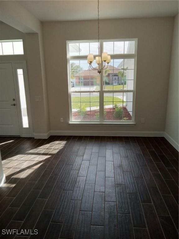 unfurnished dining area featuring dark wood-type flooring and an inviting chandelier