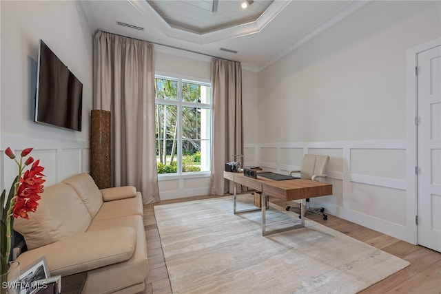 office featuring crown molding, a tray ceiling, and light wood-type flooring