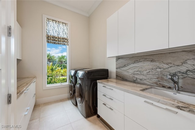 clothes washing area featuring washer and clothes dryer, sink, crown molding, light tile patterned floors, and cabinets