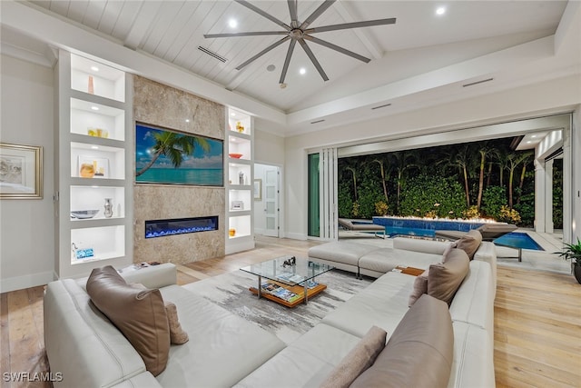 living room with built in features, light hardwood / wood-style flooring, vaulted ceiling with beams, and a fireplace