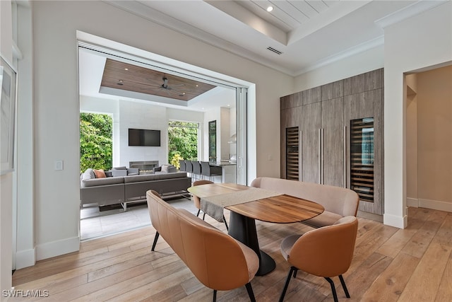 dining room featuring light hardwood / wood-style flooring, ceiling fan, and a raised ceiling