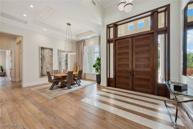 entrance foyer with a tray ceiling, light wood-type flooring, and a healthy amount of sunlight