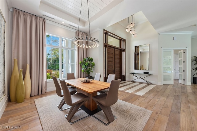 dining room featuring an inviting chandelier, a tray ceiling, and light hardwood / wood-style floors