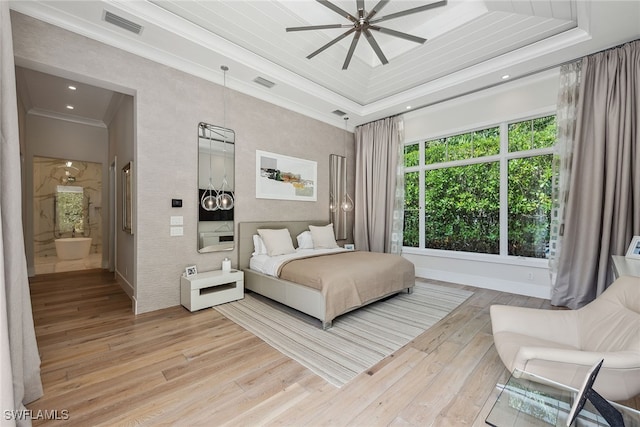 bedroom featuring ensuite bath, ornamental molding, light wood-type flooring, a raised ceiling, and ceiling fan