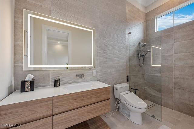 bathroom with tile patterned floors, toilet, vanity, tile walls, and a tile shower