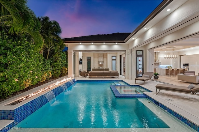 pool at dusk featuring an in ground hot tub, a patio area, pool water feature, and outdoor lounge area