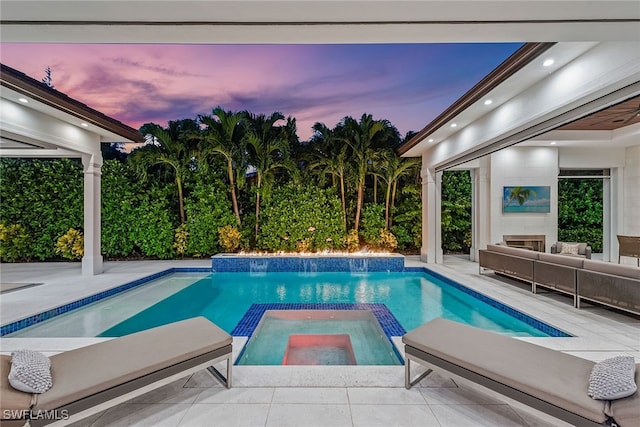 pool at dusk featuring an in ground hot tub, pool water feature, and a patio