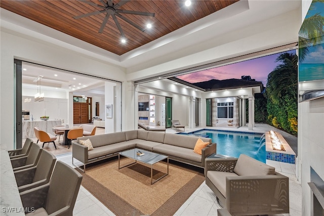 pool at dusk featuring pool water feature and ceiling fan