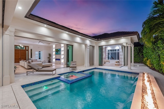 pool at dusk with an in ground hot tub, outdoor lounge area, pool water feature, a patio area, and ceiling fan