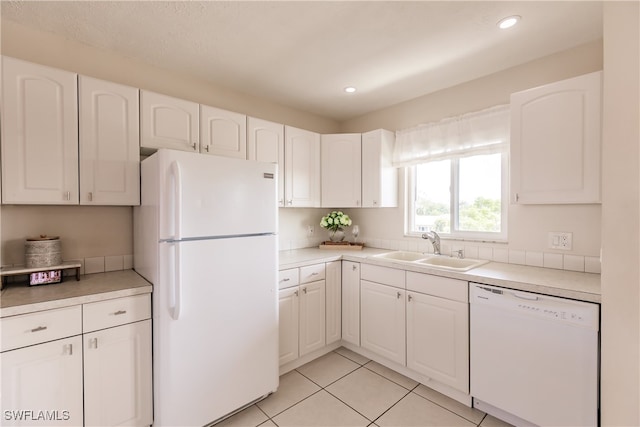 kitchen with white cabinetry, sink, light tile patterned floors, and white appliances