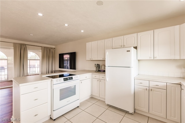 kitchen with white appliances, white cabinetry, light tile patterned floors, and kitchen peninsula