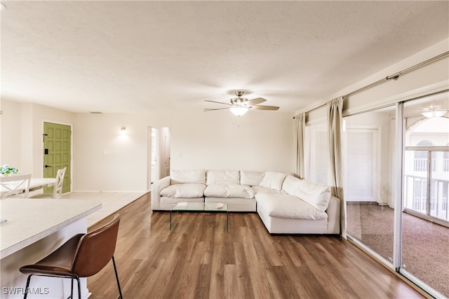 living room with dark wood-type flooring, a textured ceiling, and ceiling fan