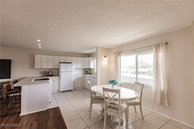 dining area featuring a textured ceiling, light tile patterned flooring, and sink