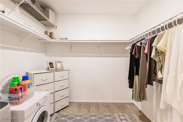 spacious closet with washer and clothes dryer and light colored carpet