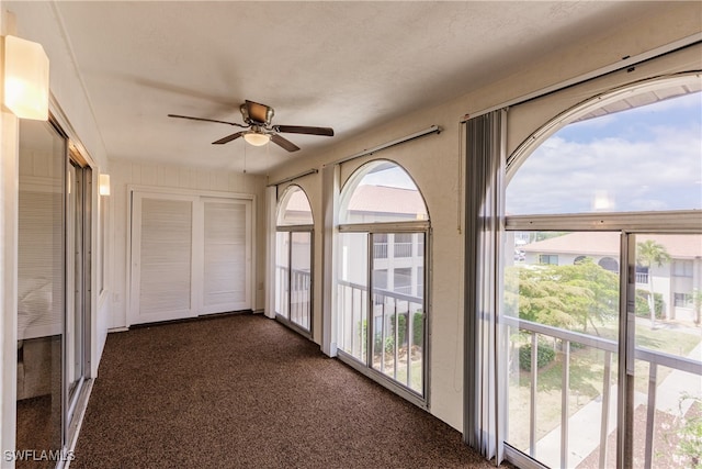 unfurnished sunroom featuring ceiling fan and a wealth of natural light