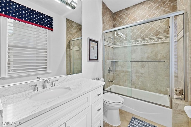 full bathroom with toilet, vanity, shower / bath combination with glass door, and tile patterned flooring