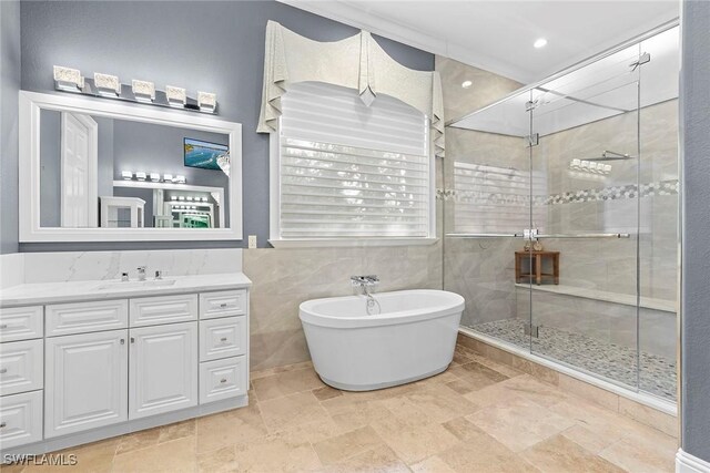 bathroom featuring plus walk in shower, vanity, and tile walls