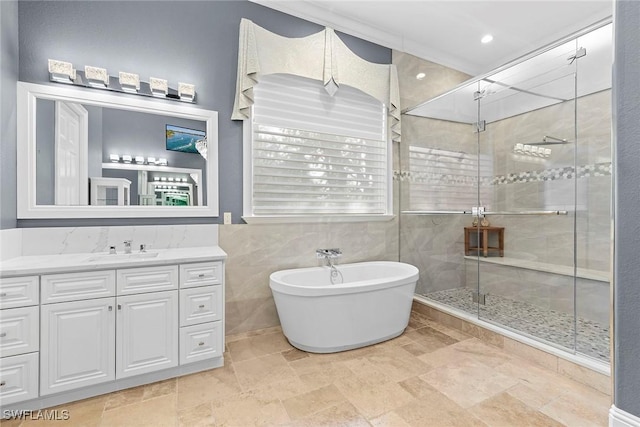 bathroom featuring independent shower and bath, vanity, and tile walls