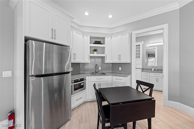 kitchen featuring sink, crown molding, appliances with stainless steel finishes, white cabinetry, and tasteful backsplash