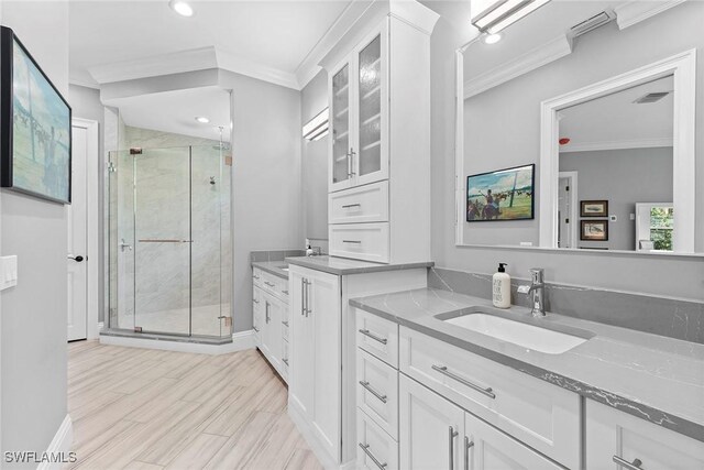 bathroom with a shower with door, ornamental molding, hardwood / wood-style floors, and vanity