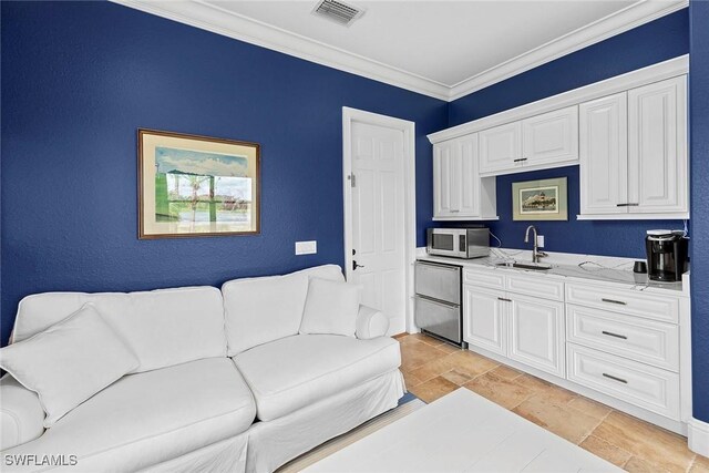 kitchen featuring white cabinetry, sink, light stone countertops, light tile patterned floors, and ornamental molding