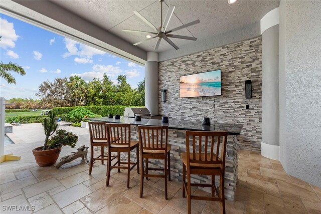 view of patio featuring exterior bar, ceiling fan, exterior kitchen, and a grill