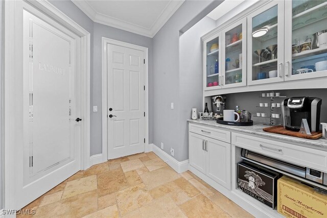 bar featuring light stone countertops, white cabinetry, and ornamental molding