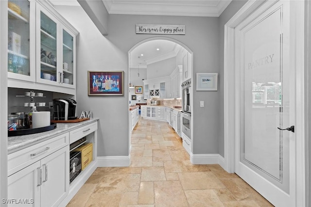 bar featuring ornamental molding and white cabinets