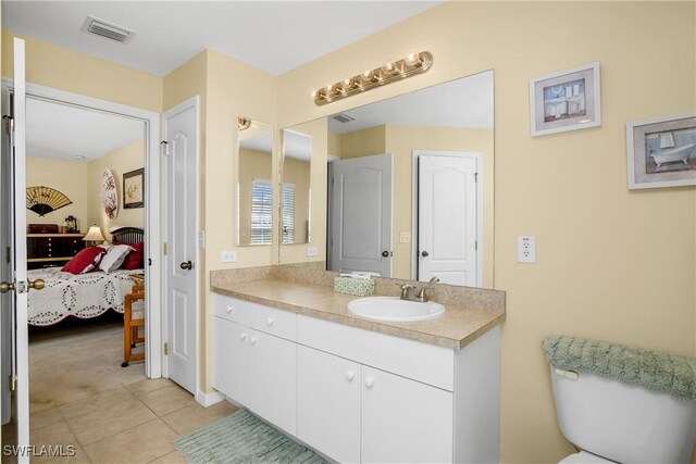 bathroom with toilet, vanity, and tile patterned floors