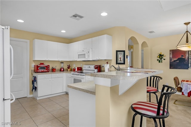 kitchen featuring white cabinetry, kitchen peninsula, a breakfast bar area, hanging light fixtures, and white appliances