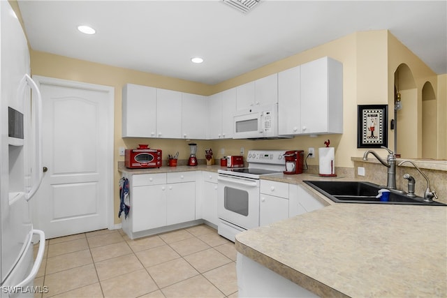 kitchen with white appliances, sink, light tile patterned flooring, and white cabinets