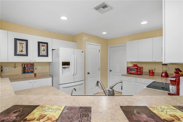 kitchen featuring stove, white cabinetry, sink, and white fridge with ice dispenser