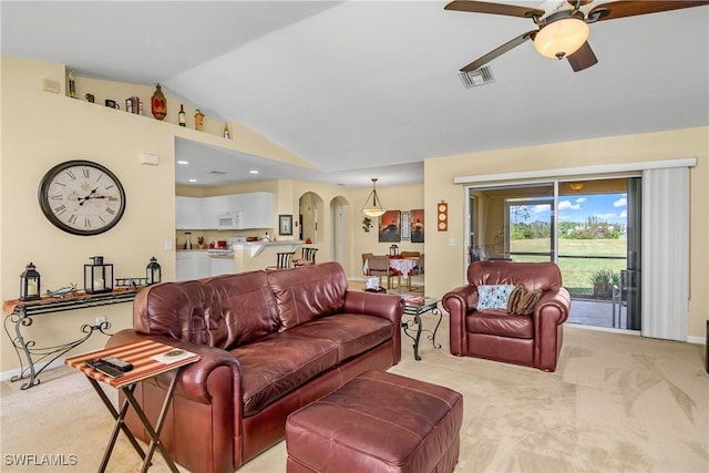 carpeted living room featuring visible vents, lofted ceiling, arched walkways, baseboards, and ceiling fan