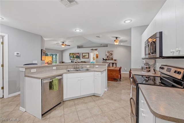 kitchen featuring a kitchen island with sink, sink, vaulted ceiling, appliances with stainless steel finishes, and white cabinetry