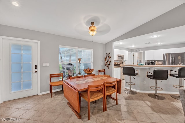 dining room with ceiling fan, light tile patterned flooring, and vaulted ceiling