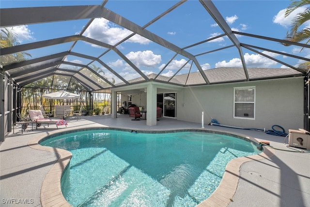 view of swimming pool with a patio, glass enclosure, and ceiling fan