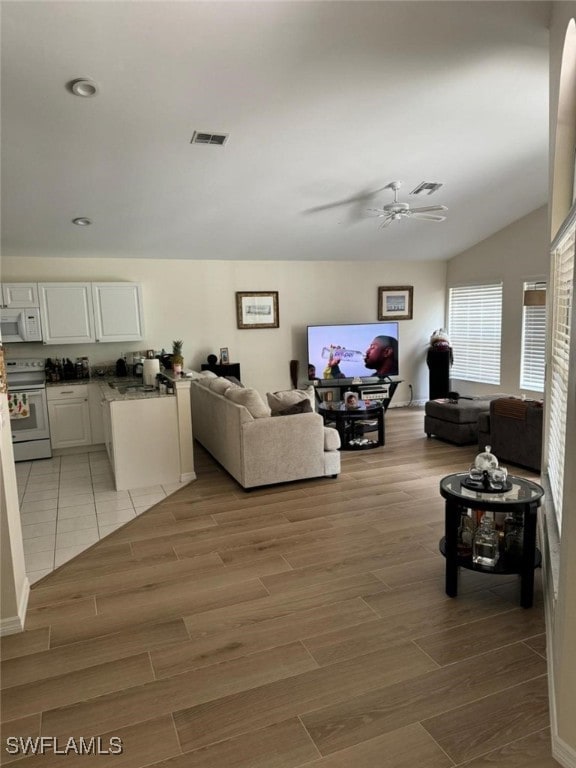 living room featuring vaulted ceiling, light wood-type flooring, and ceiling fan