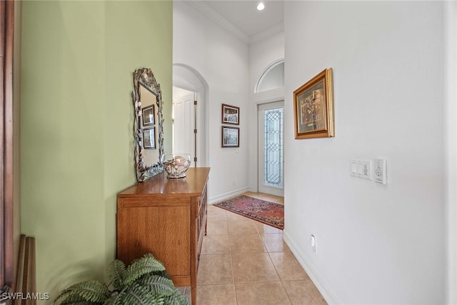 foyer entrance with light tile patterned floors, a towering ceiling, and ornamental molding