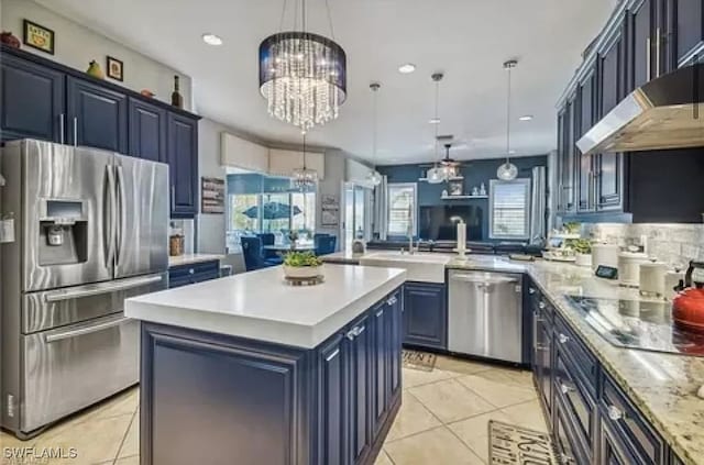 kitchen featuring blue cabinetry, appliances with stainless steel finishes, decorative light fixtures, and a kitchen island