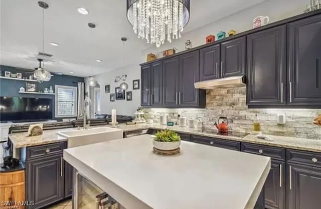 kitchen featuring kitchen peninsula, decorative backsplash, a center island, and hanging light fixtures