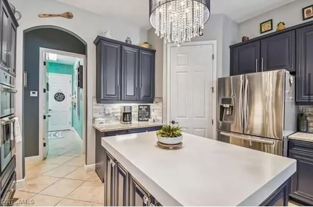 kitchen featuring a kitchen island, pendant lighting, light tile patterned floors, appliances with stainless steel finishes, and tasteful backsplash